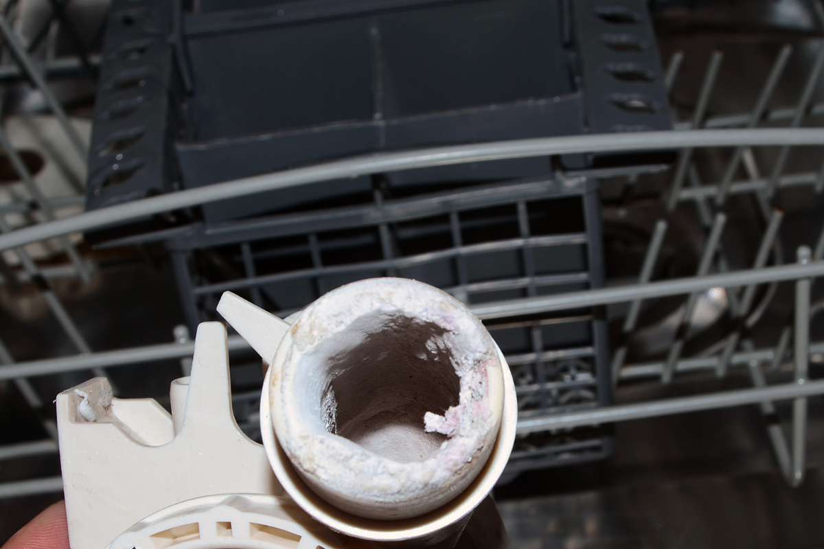 Dishwasher part coated in white hard water mineral deposits