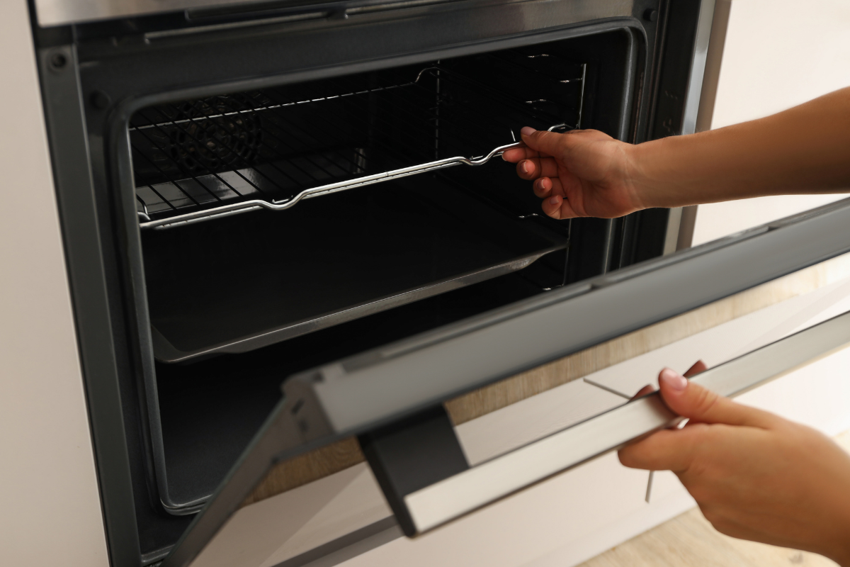 Person removing an oven rack to check for loose parts causing noise