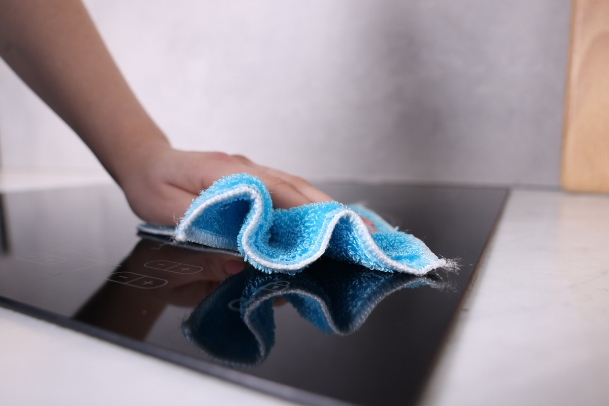 Hand wiping the touch controls of an induction cooktop with a cloth